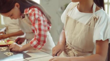 Mutfak masasında çocuklarla yemek pişirirken önlüklü küçük Asyalı kız yemek pişirme dersi sırasında şampiyon oldu.