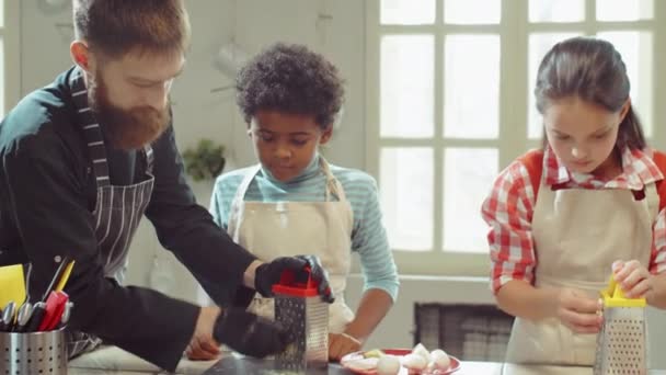 在烹饪大师课上 戴着围裙和手套的厨师帮助小鸟小男孩做烤奶酪 — 图库视频影像