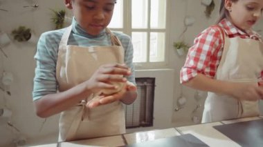 Önlüklü tatlı melez çocuk diğer çocuklarla ana yemek kursunda şekil alıyor.