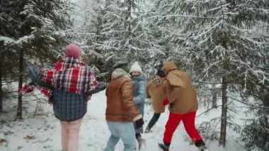 Kış günü gülümseyen ve karlı ormanda koşan heyecanlı genç arkadaşların çekimlerinin ardından