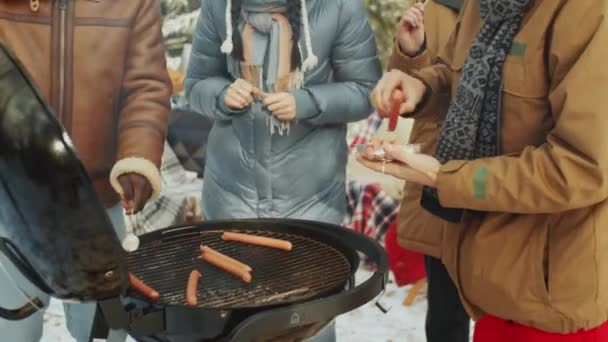 Hombre Poniendo Salchichas Parrilla Barbacoa Mientras Cocina Alimentos Con Amigos — Vídeos de Stock