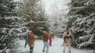 Heyecanlı çoklu etnik arkadaşların kış ormanlarında kartopu savaşı yaparken görüntüyü yakınlaştır