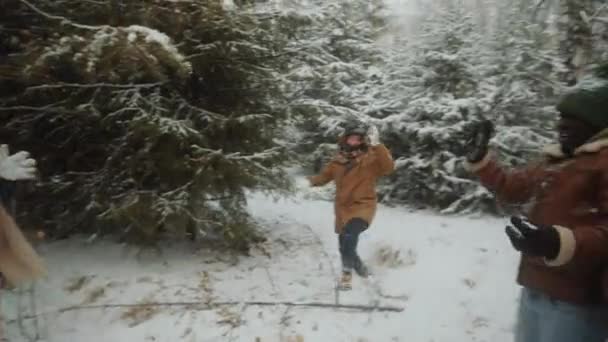 冬の日に森の中で楽しみながら雪合戦をする興奮した若い男女の手持ちカメラ — ストック動画