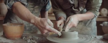 Sınıfta yaşlı çömlekçiyle çalışırken sünger kullanan genç bir kadın.