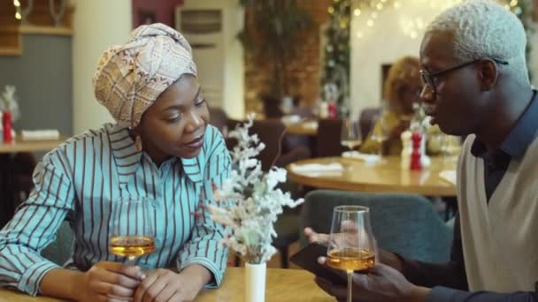 Молодые Афроамериканка Мужчина Обсуждают Смартфоне Выпивая Вино Ресторане — стоковое видео