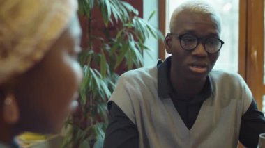 Kafede oturan ve kız arkadaşıyla konuşan Afrikalı genç bir Amerikalının omzunun üstünden.