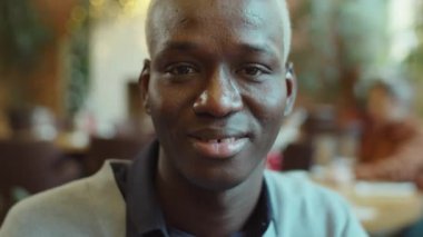 Kafede gülümseyen ve kameraya poz veren neşeli Afro-Amerikalı adamın portresi.