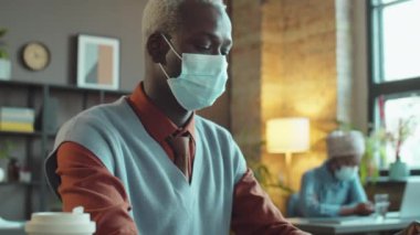 Afrika kökenli Amerikalı iş adamının masaüstü bilgisayarda yazı yazarken görüntülerini yukarı kaldır.