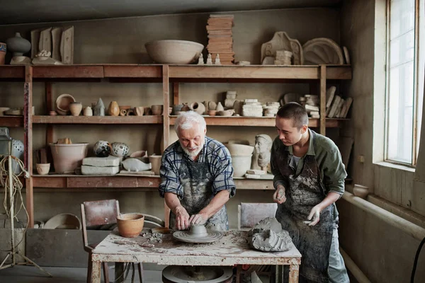 Люди, создающие посуду из глины в мастерской — стоковое фото