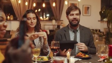 Bir grup modern genç arkadaş yemek masasında oturmuş 