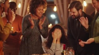 Çekici beyaz kadın, doğum gününü en iyi arkadaşlarıyla kutluyor dilek diliyor ve doğum günü pastası mumları üflüyor.