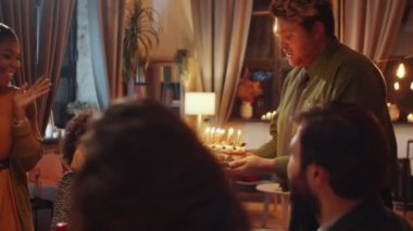 Güzel siyah kadın en iyi arkadaşlarıyla doğum gününü kutluyor, dilek diliyor ve doğum günü pastası mumlarını üflüyor.
