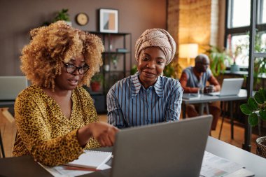 İş kadınları ofiste dizüstü bilgisayar kullanıyor.