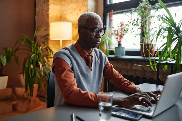 Homme d'affaires africain tapant sur ordinateur portable à la table — Photo