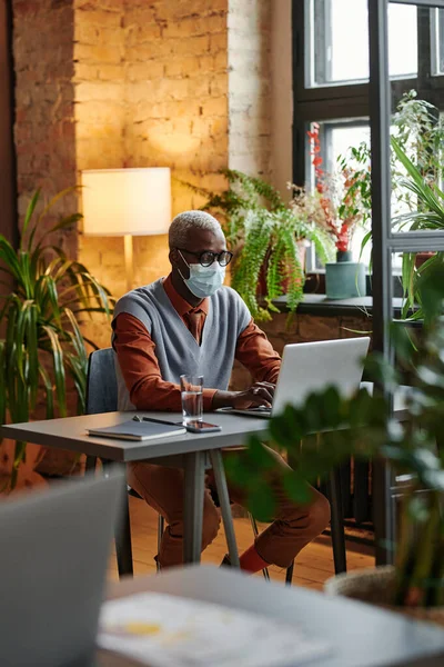 Homme d'affaires en masque travaillant sur ordinateur portable — Photo