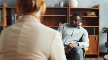 Kafkasyalı bir adam kanepede oturuyor, yastığa sarılıyor ve kadın psikoloğa çift terapisi sırasında Afrikalı Amerikalı erkek arkadaşı hakkında şikayette bulunuyor.