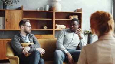 Genç Afrikalı Amerikalı bir adamın koltukta oturup kadın psikologa beyaz partnerinden şikayet etmesi.