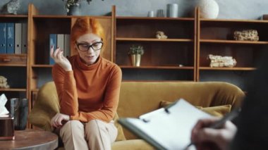 Depresyonda olan orta yaşlı, kızıl saçlı bir kadın kanepeye oturuyor, gözlüğünü çıkarıyor ve terapi sırasında tanınmayan psikologlara şikayet ediyor.