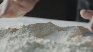 Erkek fırıncının eli, tam ortasında un yığını oluşturan yakın çekim görüntüsü.