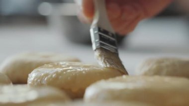 Pişirmeden önce çiğ hamburgerin üstüne fırçalayarak yakın plan yumurta yıkama.