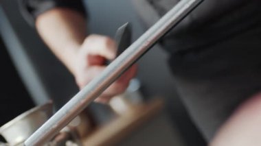 Erkek şefin bileme bıçağını bilenen ellerinin Hollanda açılı çekimini kapat.