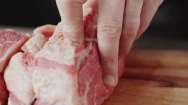 Mutfakta yemek pişirirken ahşap tahtada çiğ et keserken yakın çekim.