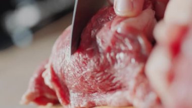 Erkek ellerinin bıçakla çiğ et keserken son derece yakın çekim görüntüleri.