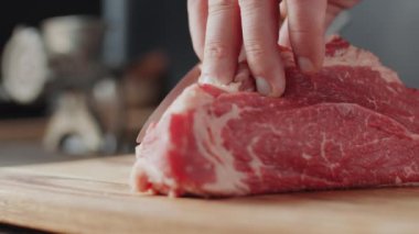 Erkek elleri yakın çekim Tahtada bıçakla çiğ et keserken