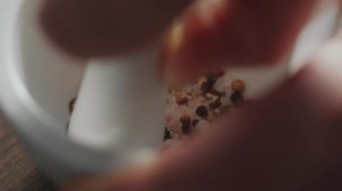 Biber ve tuz kristallerini havan ve tokmakla ezen ellerin aşırı yakın çekimi.