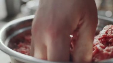 Erkek elinin metal kasede kıyma ile baharatı karıştırdığı yakın çekim.