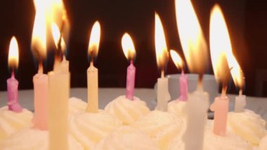 Doğum günü pastasının üzerindeki yanan mumları tereyağlı kremayla yakınlaştır.