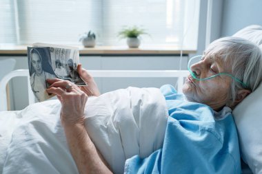 Hasta kıdemli kadın eski fotoğraflarına bakıyor.