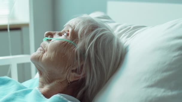 治療中に病棟のベッドの上に寝そべって鼻カヌラを持つシニア白人女性 — ストック動画