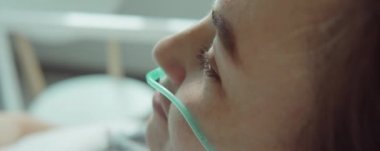 Burun kanülü olan genç bir kadının hastanede tedavi görürken yakın plan fotoğrafı.