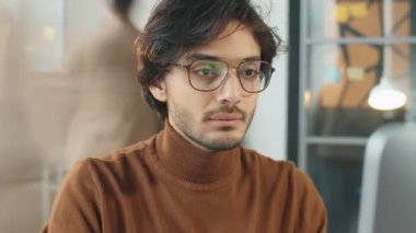 Ofiste çalışırken bilgisayar kullanan Orta Doğulu yakışıklı iş adamının görüntüsünü büyüt.