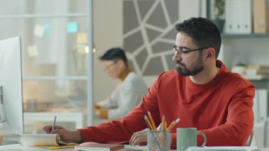 İşadamının not aldığı, açık ofiste çalışırken bilgisayar kullandığı ve kağıt okuduğu görüntüleri büyüt