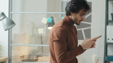 Orta Doğulu genç işadamının iş günü açık ofiste cep telefonu kullanırken görüntüsünü büyüt