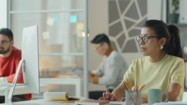 Güzel İspanyol iş kadını bilgisayarda yazı yazıyor ve açık ofiste çalışırken notlar alıyor.