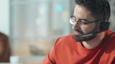 Telsiz kulaklıklı bir adamın çağrı merkezinde çalışırken müşteriyle konuşması.