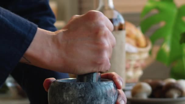 Közelkép a kezek felismerhetetlen ember őrlés fűszerek kő habarcs és mozsártörő főzés közben a konyhában