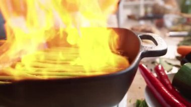 Profesyonel aşçının şömineyi tutuşturduğu yakın plan fotoğraf. Sonra da alev alırken metal maşayla kuşkonmaz fırlatırken.