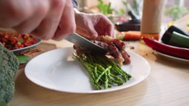 Profesyonel şefin ellerini yakın çekimde kuşkonmaz üzerine kızarmış et koyarak restoran mutfağında yemek servis ederken beyaz tabağa koyun.