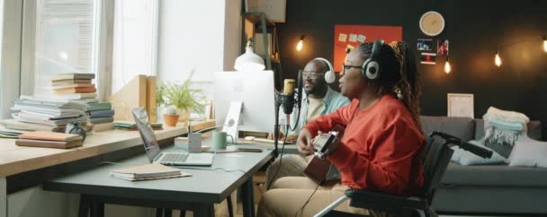 Mujer Afroamericana Auriculares Sentada Silla Ruedas Tocando Guitarra Cantando Micrófono — Vídeos de Stock