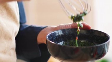 Mutfakta yemek hazırlarken taze sebze ve zeytinyağı karıştırırken çırpılmış çırpılmış taze sebze kullanan erkek aşçıların yakın çekim görüntüsü