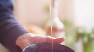 Erkek aşçının, cam şişeden zeytinyağını, salata hazırlarken taze sebzelerle dolu kaseye boşalttığı yakın çekim görüntüsü.