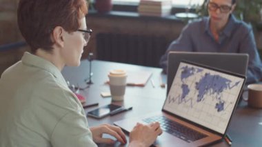 İş kadını ofis masasında çalışırken dizüstü bilgisayardaki çizelgeleri ve bilgi haritasını analiz ediyor.