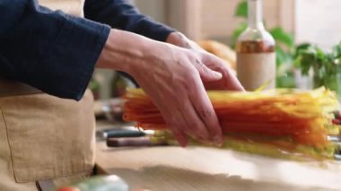 Erkek aşçının ellerini aşağı doğru eğ ve mutfak masasına pişmemiş spagetti at.