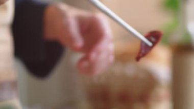 Erkek aşçının elleri, metal mutfak cımbızı kullanırken güneşte kurutulmuş domatesleri pişirilmiş makarnanın üstüne koyarken yakın çekim.