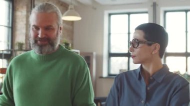 Olgun iş adamı, kadın meslektaşıyla ofiste yürüyor ve iş günlerinde bir şeyler tartışıyor.