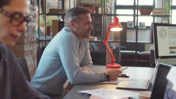 近代的なオフィスの同僚とのコワーキング テーブルに座って議論をしている2人の成熟したビジネスマンの追跡ショット — ストック動画